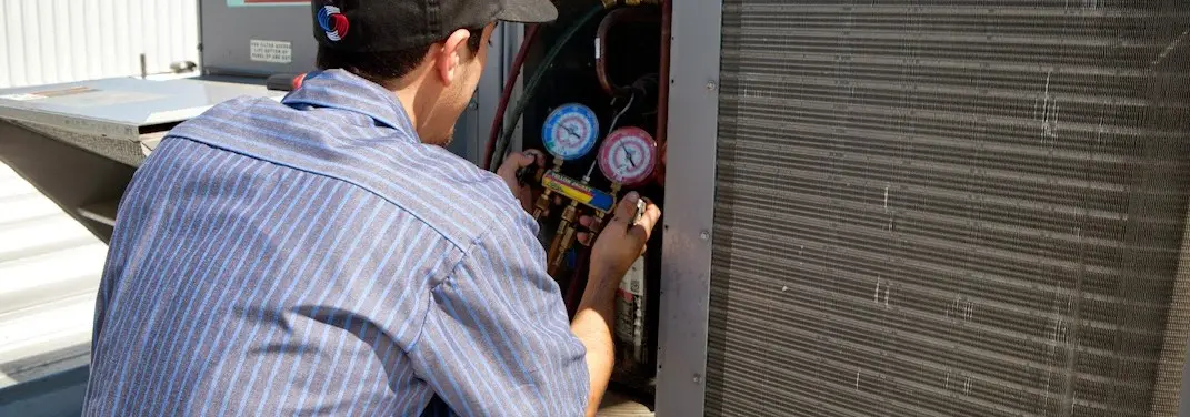 HVAC technician servicing a condenser unit in Bern